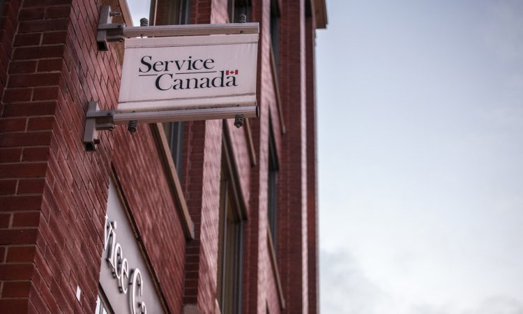 Picture of a Service Canada sign on the exterior of their red brick office building in Toronto