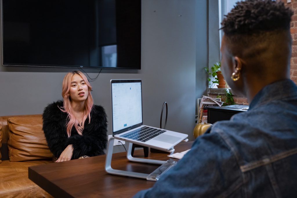 Transfeminine and non-binary colleagues talking in office.