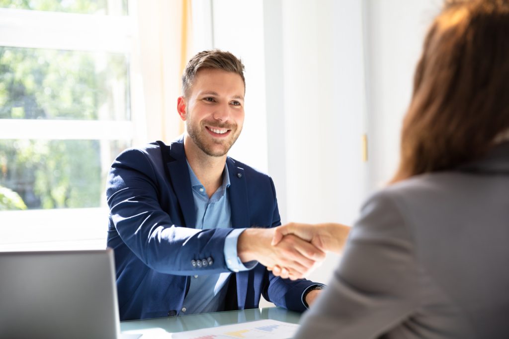 Man smiling while shaking hands during job interview