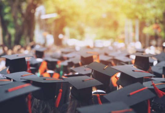 Top view of group of people wearing graduation caps outside