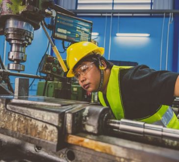 Man working in factory looking closely at piece of machinery