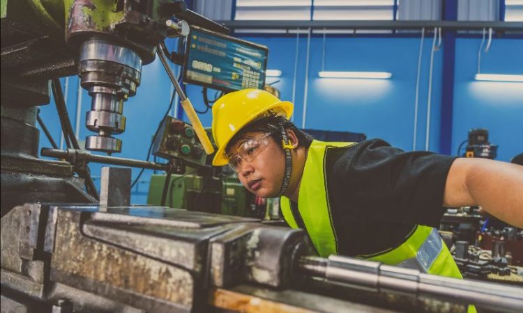 Man working in factory looking closely at piece of machinery