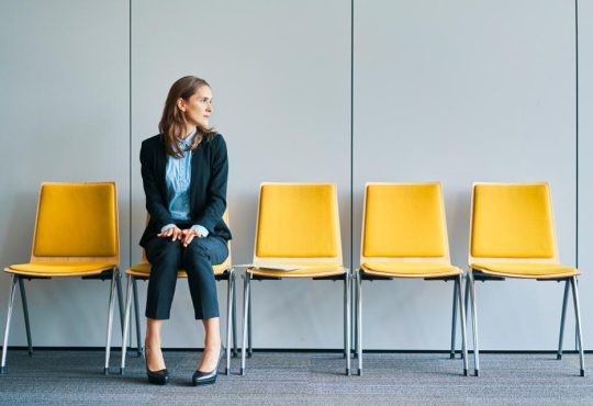 Woman sitting in yellow chair in waiting room of office