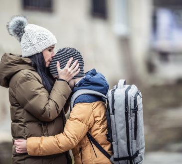 Woman wearing winter jacket hugging son outside