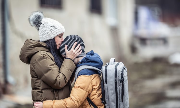 Woman wearing winter jacket hugging son outside