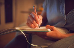 Close-up of person's hands writing in journal