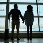 Silhouetted couple holding hands at airport