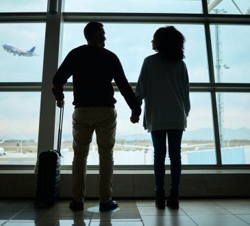 Silhouetted couple holding hands at airport