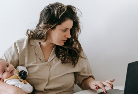 Woman working from home with baby in hand