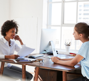 Women working together at desk with computer