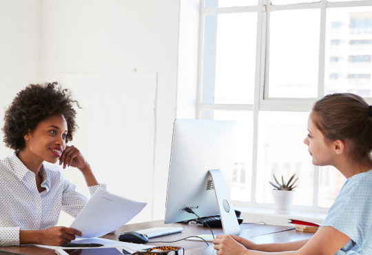 Women working together at desk with computer