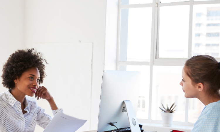 Women working together at desk with computer