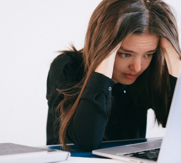 Woman looking at laptop and feeling stressed.