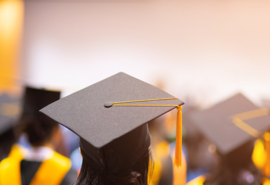 Students seated in graduation regalia with caps and gown