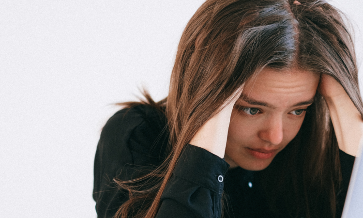 Woman looking at laptop and feeling stressed.