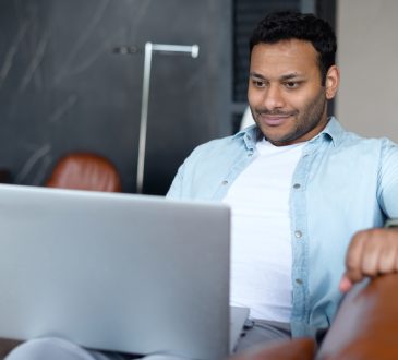 Man looking at laptop slightly smiling