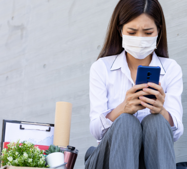 Woman sitting down using phone after getting fired due to pandemic layoffs