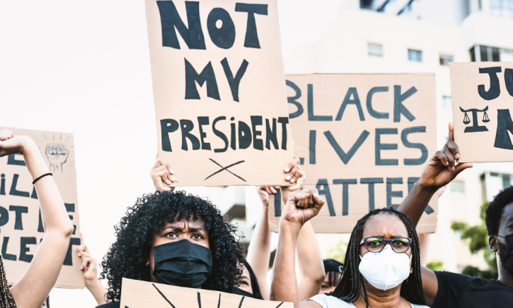 Black Lives Matter protest during the pandemic, with people holding signs reading "not my president" and "black lives matter."