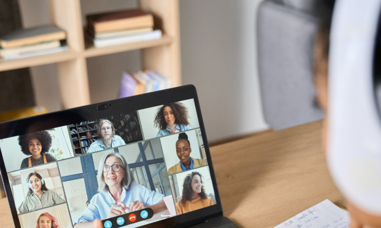 Student wearing headphones and watching live online class with professor and other students on the screen.