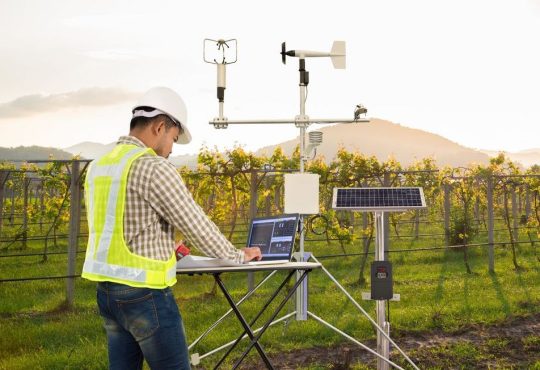 Agronomist using tablet computer to collect data with meteorological instrument in grape field