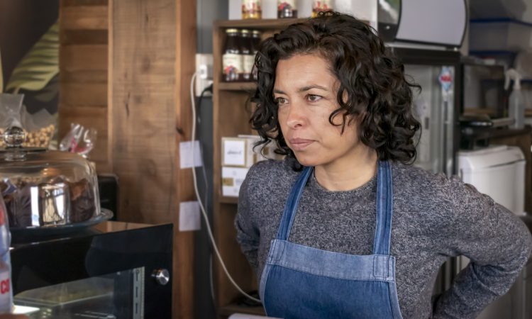 Waitress wearing apron standing behind bar