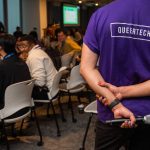 Person wearing purple QueerTech tshirt at conference.