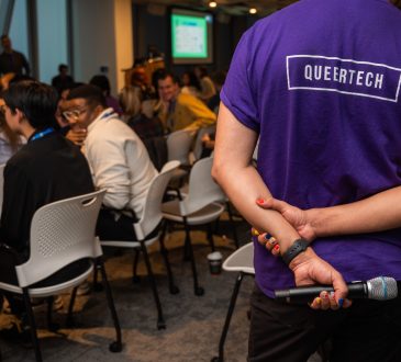 Person wearing purple QueerTech tshirt at conference.