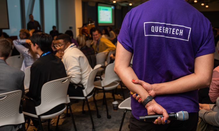 Person wearing purple QueerTech tshirt at conference.