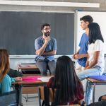 Teens talking with teacher in classroom