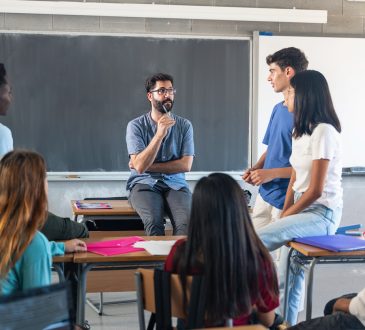Teens talking with teacher in classroom