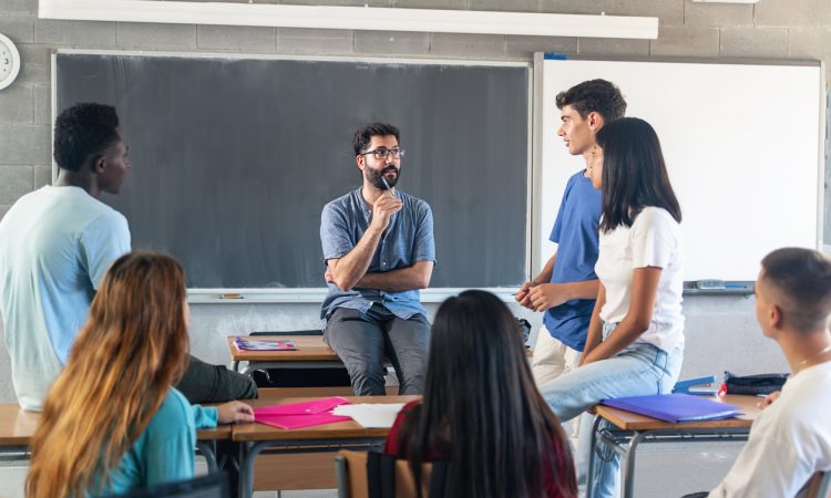 Teens talking with teacher in classroom