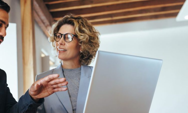 Two colleagues using laptop in meeting