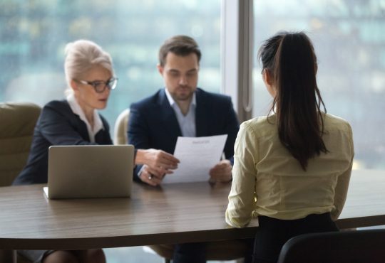 Person sits across from two interviewers in panel interview