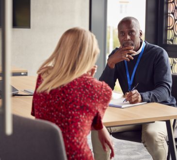 Two people sitting across table and talking