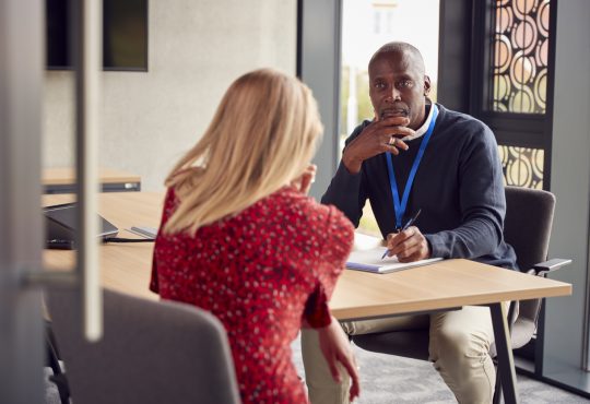 Two people sitting across table and talking