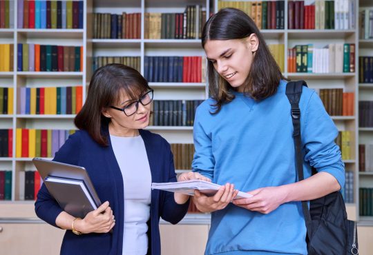 female teacher helping male student.