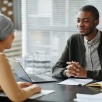 Two people sitting across desk from each other in job interview in office