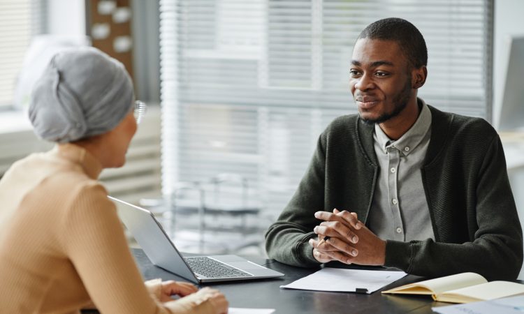 Two people sitting across desk from each other in job interview in office