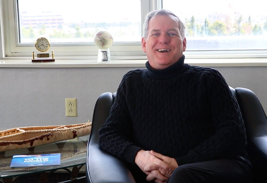 Rob Shea sits in an armchair smiling during interview