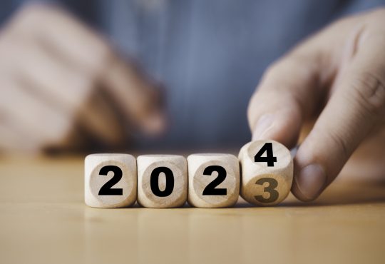 Hand flipping of 2023 to 2024 on wooden block cube.