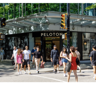 Photo of a busy street corner intersection with many people walking.