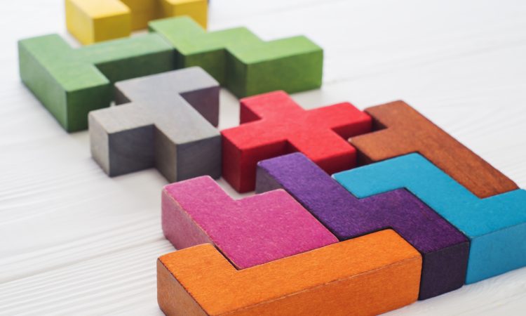 The image shows colorful 3D puzzle pieces resembling Tetris blocks arranged on a white surface.