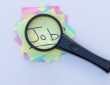 Magnifying glass on top of sticky notes reading "job"