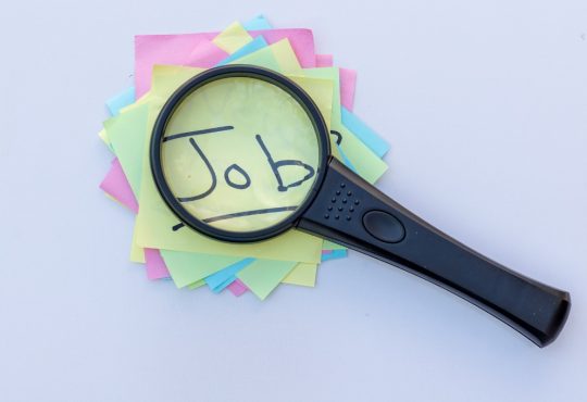 Magnifying glass on top of sticky notes reading "job"