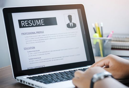 Close up of someone working on a resume on an open laptop.