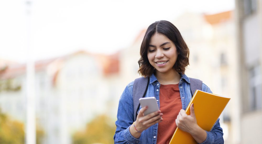 Student messaging on phone walking home after class