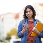 Student messaging on phone walking home after class