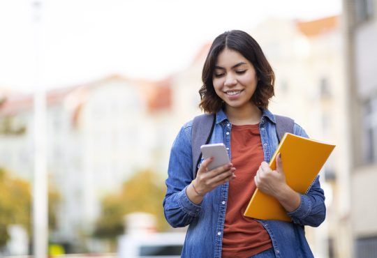 Student messaging on phone walking home after class