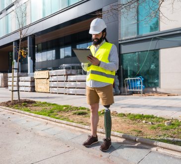 Engineer with prosthetic leg working on construction site wearing protective equipment