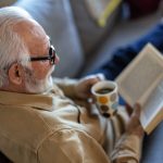 Man reading book on couch with coffee